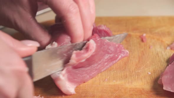 Women's hands cut meat with a kitchen knife. Cooking meat dishes in the home kitchen.