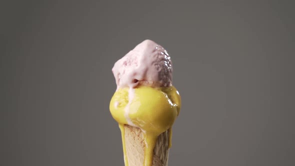 Yellow and pink Ice cream cone gradually melting on isolated background. Sugar concept. Time lapse alt