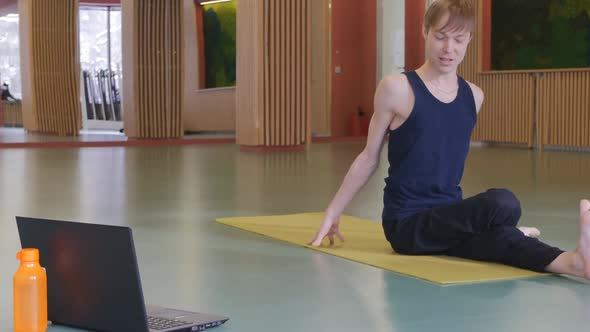 a Young Handsome Male Yoga Coach Conducts an Online Individual Class Via the Internet Using a Laptop alt
