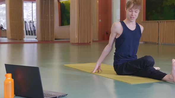 a Young Handsome Male Yoga Coach Conducts an Online Individual Class Via the Internet Using a Laptop