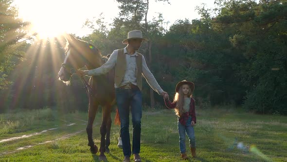 A Cowboy with a Horse and His Beautiful Daughter are Walking in the Pasture alt