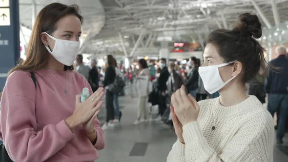 Two Women in Medical Mask Portrait Looking at Camera in Airport Terminal Using Antiseptic for Hands alt