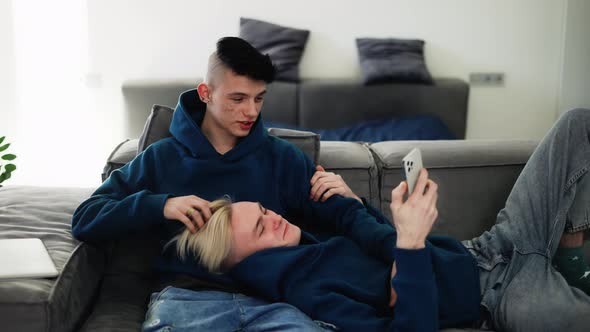 Happy Men Homosexual Couple Sit on Sofa and Using Smartphone Talking alt