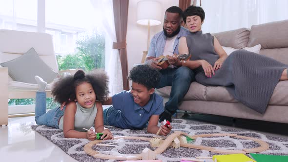 African American boy and girl playing toy cars racing at home together with parent