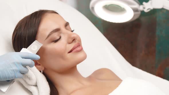 Lovely Female Receiving Facial Treatment with Cosmetology Apparat alt