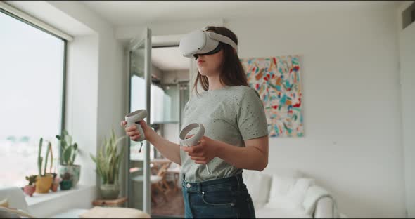 Young woman enjoying virtual reality experience with goggles and handle control alt
