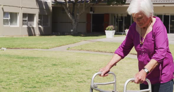 Senior woman walking in the park of a retirement home alt