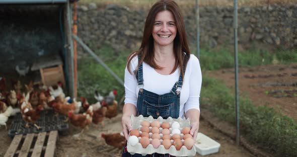Caucasian farmer woman picking up organic eggs in henhouse - Farm lifestyle and healthy food concept alt