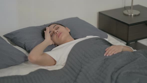 Hispanic Woman having Headache while Sleeping in Bed alt