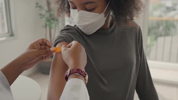 A female doctor is applying plaster to a child's shoulder after being vaccinated. 
