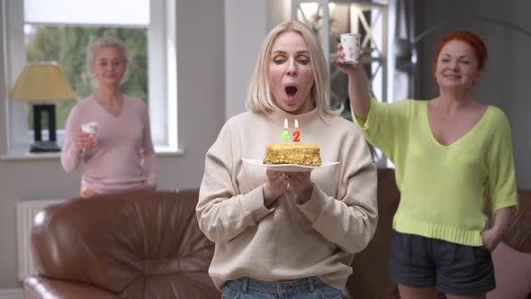 Beautiful Caucasian Adult Woman Wishing Blowing Out Candles on Birthday Cake on 42 Birthday Smiling alt