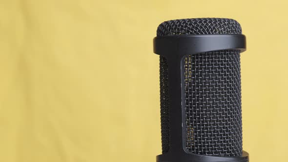 Studio Condenser Microphone Rotates on Yellow Background with Place for Text alt