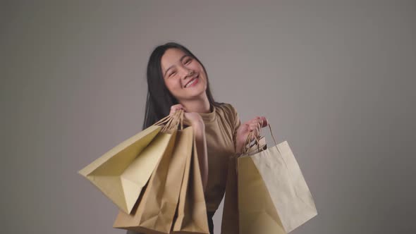 Confident asian woman happy holding shopping bag dancing smilling and looking at camera