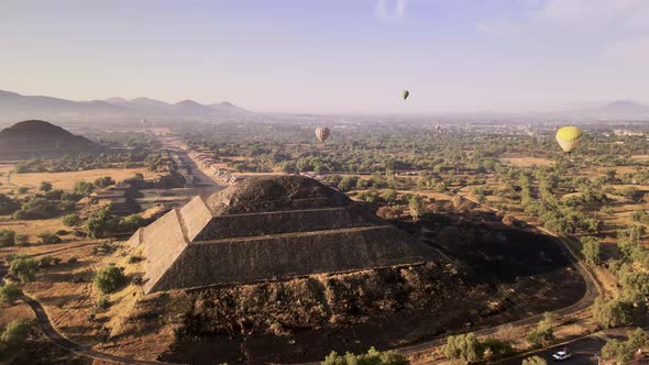 Drone footage over pyramid with hot air balloon on the back at the morning alt