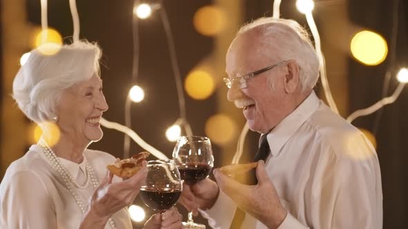 Happy Elderly Couple Eating Pizza at Christmas Party alt