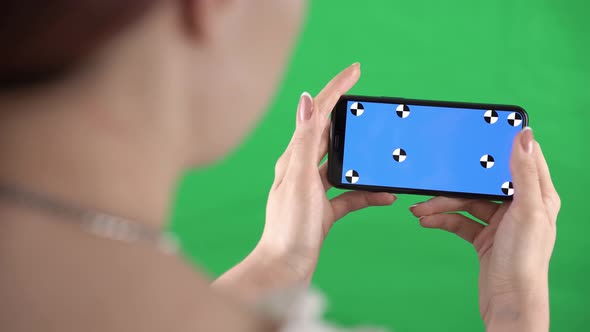 Woman is Zooming Content in Smartphone with Tracking Markers on Display and Green Screen alt