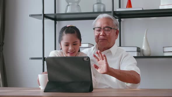 An Asian grandfather and granddaughter spending time together in the living room. alt