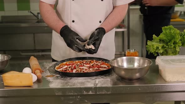 Closeup of the Chef Putting Mushrooms on Pizza with Tomatoes in the Kitchen alt