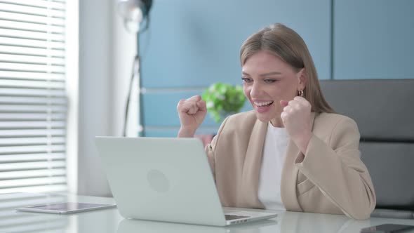 Businesswoman Celebrating Success While Using Laptop in Office alt