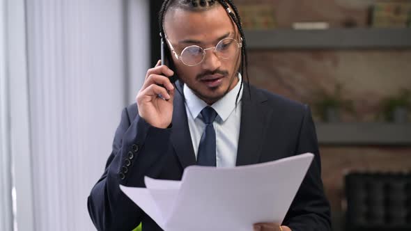A stylish black company executive is discussing something over the phone alt