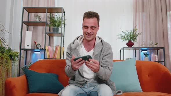 Worried Funny Young Man Boy Playing Shooter Online Video Games Celebrate Win on Smartphone at Home alt