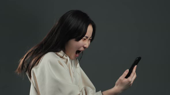 Angry Asian Woman Screaming Down, Swears with Somebody. Using Mobile Phone alt