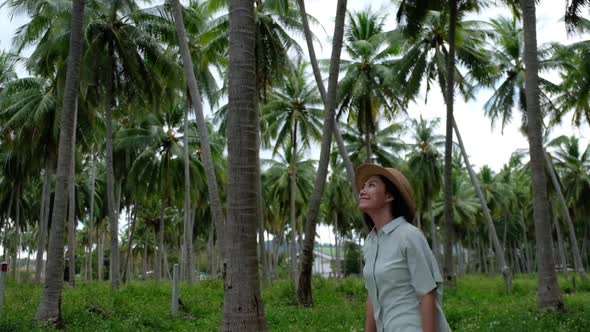 Slow motion of a young woman with hat looking at coconut trees in the garden