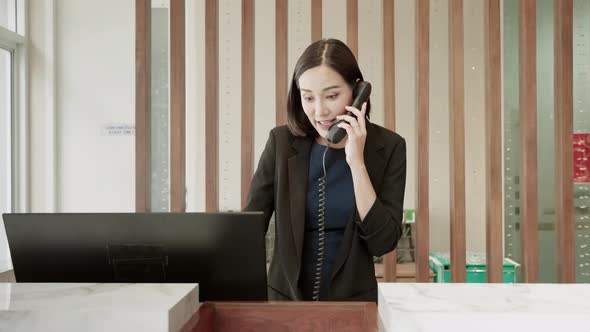 The hotel receptionist is talking on the phone with a customer to contact the hotel reservation