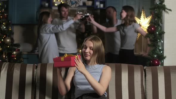 beautiful girl in room decorated garlands opens red box with Christmas gift. alt