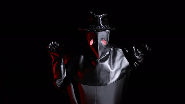 Plague Doctor Costume with Crow-like Mask Makes Funny Gestures, As If Pecking with a Beak and alt