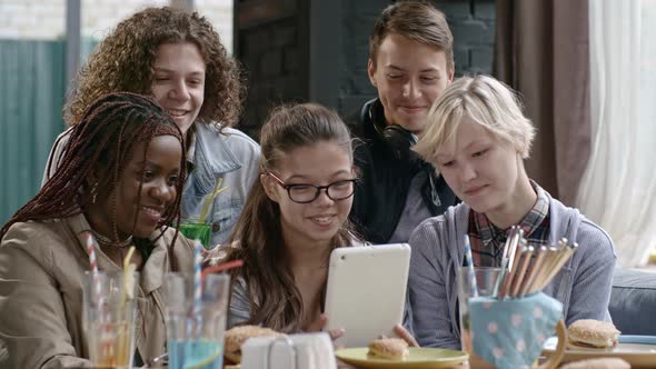Teen Friends Using Tablet and Laughing in Cafe alt