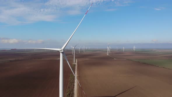 Group of Wind Driven Generators Stands Among Wide Fields
