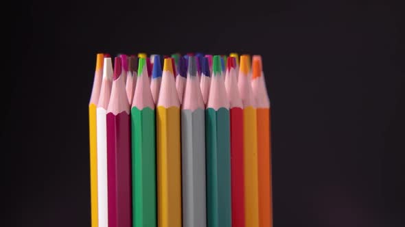 Color pencils set rotates on black background Macro shooting of drawing supplies alt