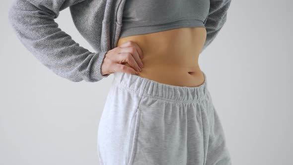 Woman Compressing the Skin on Her Stomach Checking for Excess Subcutaneous Fat alt