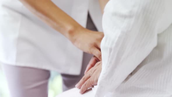 Female doctor consoling mature woman in bedroom alt