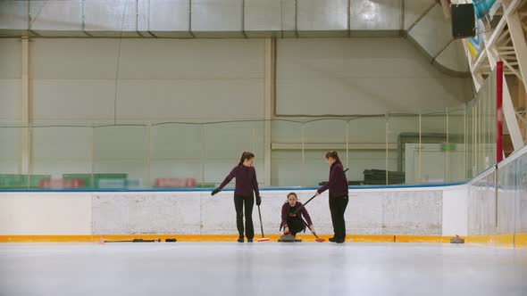 Curling Training Indoors - Team Group of Three Women Leading the Granite Stone alt