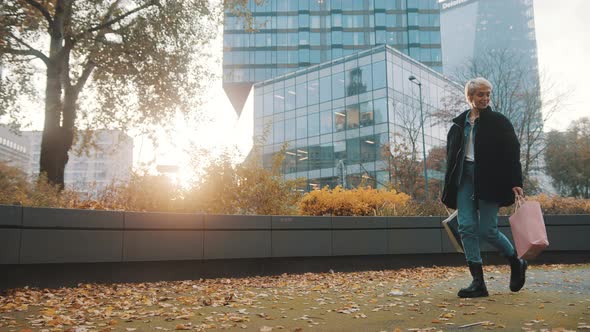 Happy Young Woman with Shopping Bags Walking in the Park with Smile Dressed in Winter Clothing alt