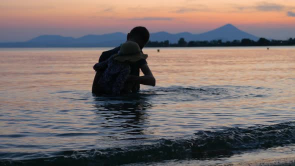Traveling Concept. Tourists in Greece on Sunset. Father and Son Swimming at Dusk. Mountain on