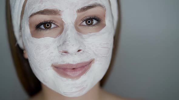 Close Portrait of Girl with Cosmetic Mask on Face Looks with Smile Into Camera alt