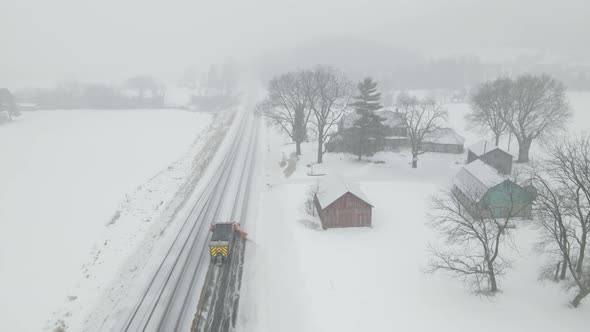 Following the sand filled snow plow clearing the rural highway during a storm.