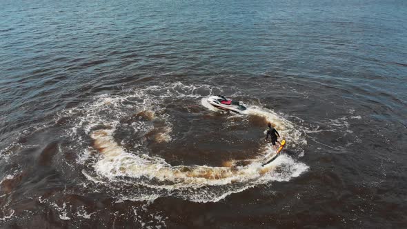 A Man Flying Around Over the Water on the Flyboard in Circles  Aerial View alt