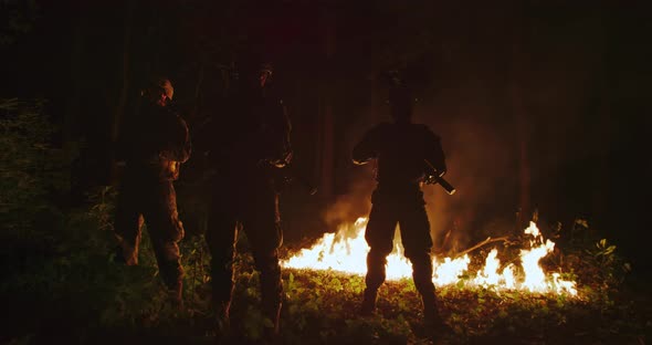 Soldiers Using Riffles in Forest at Night with Fire in Background alt