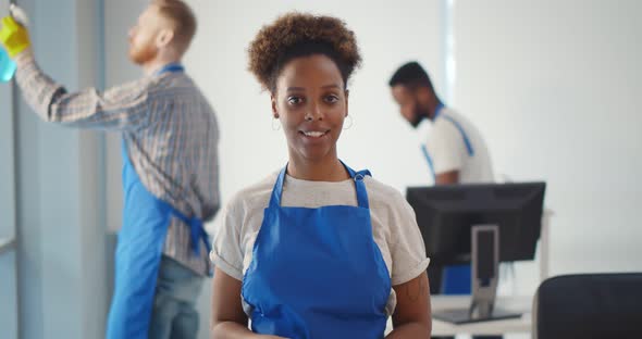 Portrait of African Female Janitor Putting on Gloves Working in Office alt