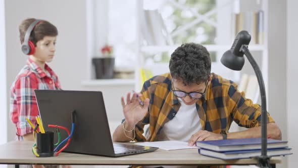 Busy Concentrated Teenage Boy in Eyeglasses Ignoring Little Brother Distracting Student From alt