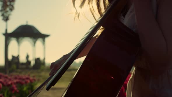 Bright Sun Beams Through Woman Profile Playing Music in Blossomed Park Outdoors alt