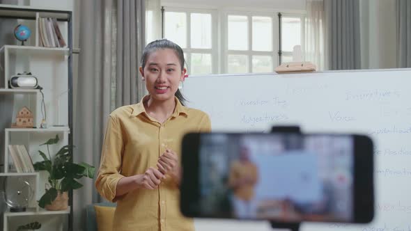 Asian Female Teacher Shoots Video By Smartphone Camera While Teaching English At Home alt