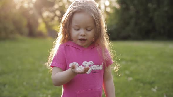 Funny Long Haired Girl Blowing Petals of Flower From Hand