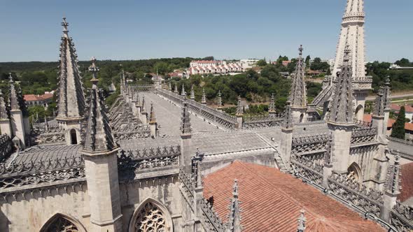 Drone flying over rooftop with gothic spires of Batalha monastery. Aerial orbit alt
