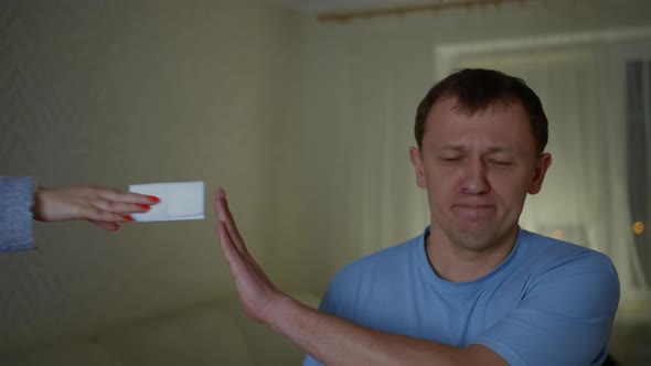 Unhappy young man refuses a napkin which we hold out a female hand alt