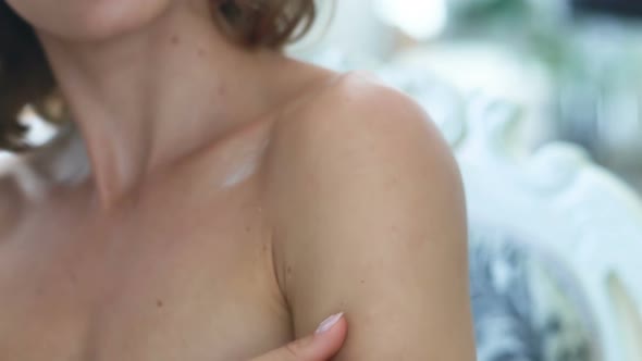 Young woman applying body lotion at morning.